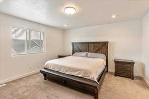 Bedroom featuring baseboards, a textured ceiling, recessed lighting, and light colored carpet