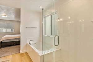 Bathroom with a garden tub, ensuite bathroom, a textured ceiling, a shower stall, and wood finished floors