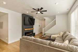 Living room featuring light wood-type flooring, stairway, a fireplace, and baseboards