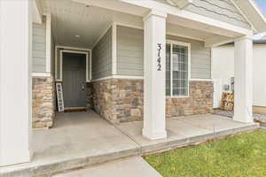 Property entrance featuring stone siding and a porch