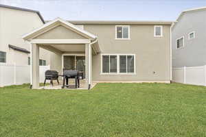 Rear view of house featuring fence private yard, stucco siding, a lawn, and a patio