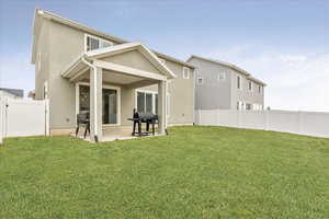 Rear view of property featuring a yard, a patio area, a fenced backyard, and stucco siding