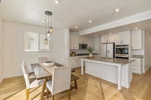 Kitchen with appliances with stainless steel finishes, light wood-style floors, and a sink