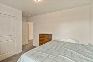 Bedroom with a textured ceiling, baseboards, and carpet flooring