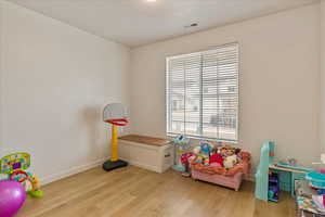 Playroom with light wood finished floors, baseboards, and visible vents