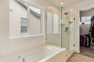 Bathroom with a spacious closet, a shower stall, and a bath