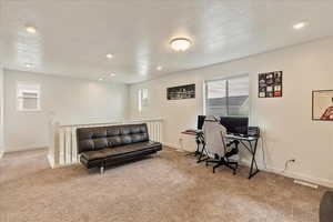 Office with baseboards, a textured ceiling, visible vents, and carpet flooring