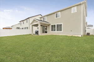 Rear view of property featuring a yard, a patio area, fence, and stucco siding