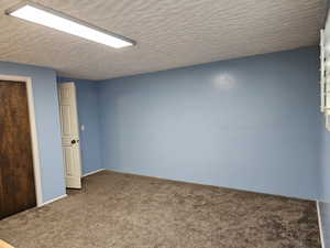 Empty room with carpet flooring and a textured ceiling