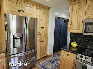 Kitchen with tasteful backsplash, baseboards, appliances with stainless steel finishes, wood finished floors, and light brown cabinetry