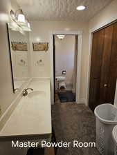 Full bath featuring a textured ceiling, a freestanding bath, and vanity