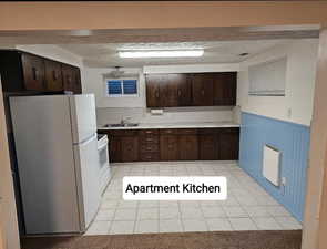 Kitchen with dark brown cabinets, white appliances, wainscoting, and a sink