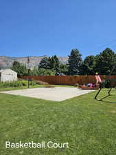 Exterior space with a mountain view, a lawn, and fence