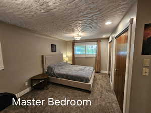 Carpeted bedroom featuring baseboards and a textured ceiling