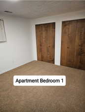 Unfurnished bedroom with carpet floors, visible vents, and two closets