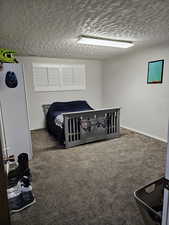 Carpeted bedroom with a textured ceiling and baseboards