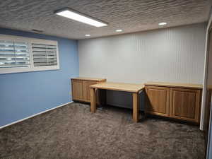 Unfurnished office featuring dark colored carpet, recessed lighting, visible vents, a textured ceiling, and baseboards