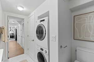 Laundry area with laundry area, a textured ceiling, stacked washing maching and dryer, and tile patterned floors