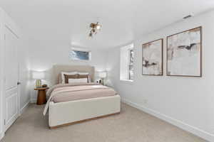 Carpeted bedroom featuring baseboards and visible vents