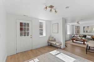 Foyer entrance featuring visible vents, baseboards, and wood finished floors