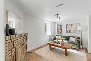 Living room with light wood-type flooring, visible vents, and baseboards