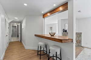 Interior space with light wood finished floors, visible vents, butcher block countertops, beamed ceiling, and baseboards