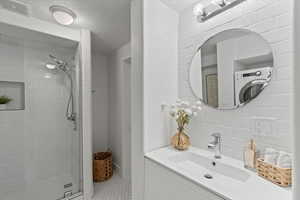 Bathroom with a textured ceiling, vanity, visible vents, a shower stall, and decorative backsplash