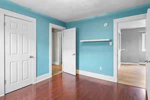 Unfurnished bedroom featuring baseboards, wood finished floors, and a textured wall