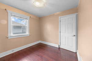 Unfurnished room featuring dark wood-style flooring, a textured ceiling, and baseboards