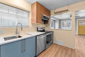 Kitchen featuring appliances with stainless steel finishes, light wood-type flooring, visible vents, and a sink