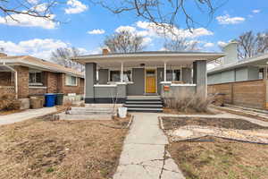 Bungalow with a chimney, fence, a porch, and brick siding