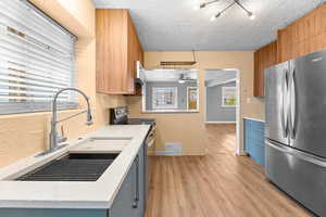 Kitchen with light wood finished floors, visible vents, ceiling fan, stainless steel appliances, and light countertops