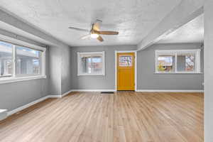 Interior space with a ceiling fan, baseboards, a textured ceiling, and light wood finished floors