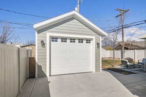 Detached garage featuring concrete driveway and fence