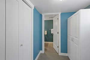 Hallway featuring visible vents, baseboards, and wood finished floors