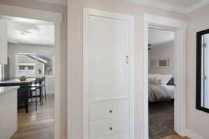 Hallway featuring light wood-style floors, baseboards, and ornamental molding