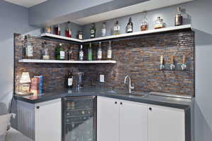 Bar with tasteful backsplash, wine cooler, a sink, and wet bar