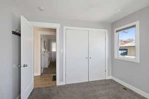 Unfurnished bedroom featuring baseboards, carpet, visible vents, and a closet