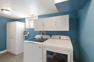 Washroom featuring laundry area, wood tiled floor, visible vents, and washing machine and clothes dryer