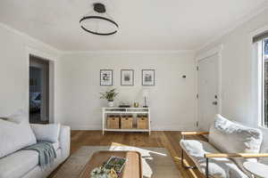 Living room featuring baseboards, ornamental molding, and wood finished floors