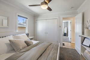 Carpeted bedroom with ceiling fan, a closet, baseboards, and crown molding