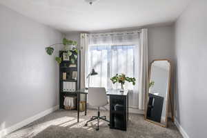 Carpeted home office featuring baseboards