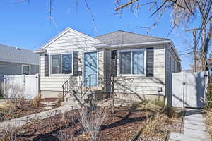 Bungalow-style house with a shingled roof, fence, and a gate