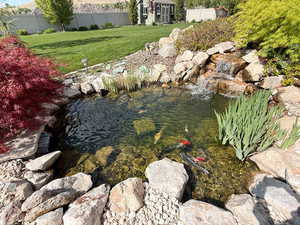 Exterior space with fence, a garden pond, and an outbuilding