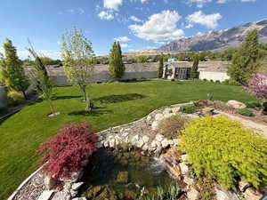 View of yard featuring a fenced backyard, a mountain view, and a small pond
