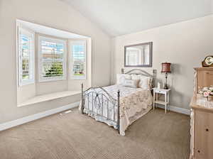 Bedroom featuring visible vents, baseboards, carpet floors, and lofted ceiling
