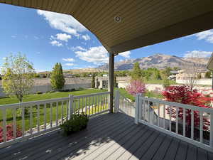 Deck with a yard, fence, and a mountain view