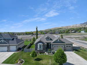 View of front of home with fence, an attached garage, a front lawn, a mountain view, and concrete driveway