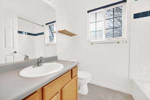 Full bathroom featuring toilet, washtub / shower combination, vanity, baseboards, and tile patterned floors