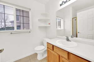 Full bath with a shower with shower door, toilet, vanity, baseboards, and tile patterned floors